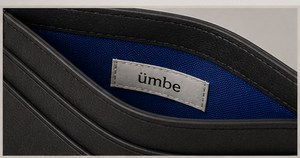 A woven silver label reading ümbe, stitched onto the cobalt lining inside the cardholder.
