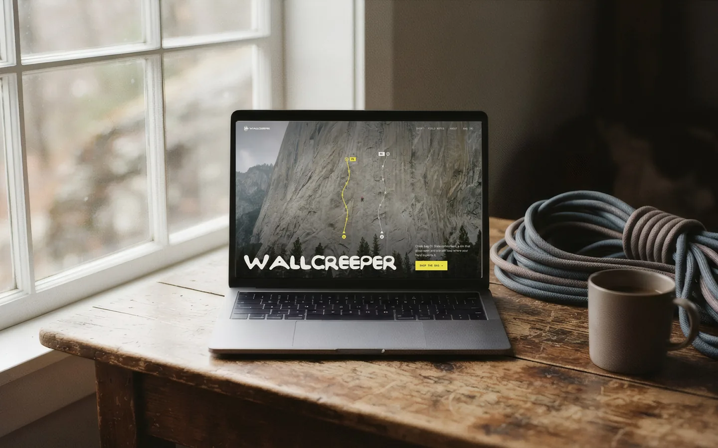 The Wallcreeper storefront on a laptop by a window, a coiled rope and a mug beside it.